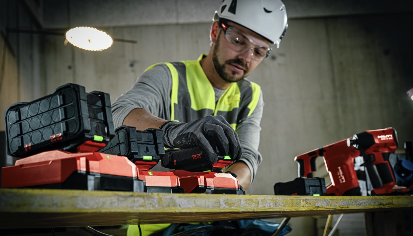Mechanical Trade Worker (plumber) putting a Nuron battery on a charger, a TE 4-22, SID 6-22 and SL 2-22 are also in background