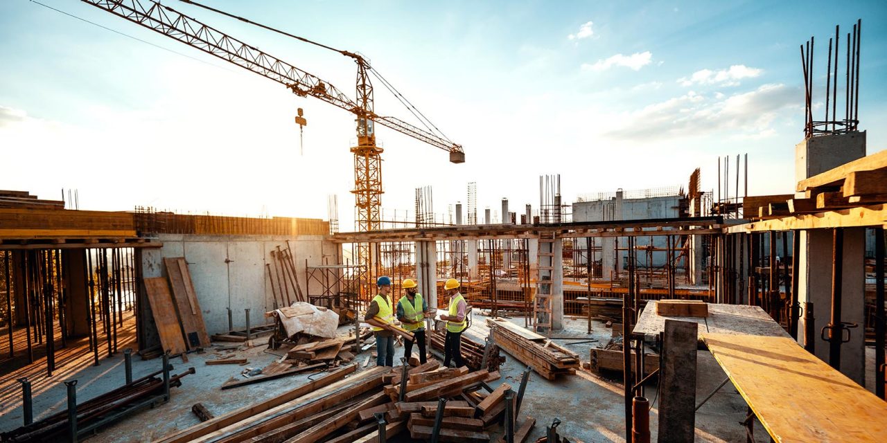 Construction industry concept - architects and engineers discussing work progress between concrete walls, scaffolds and cranes.